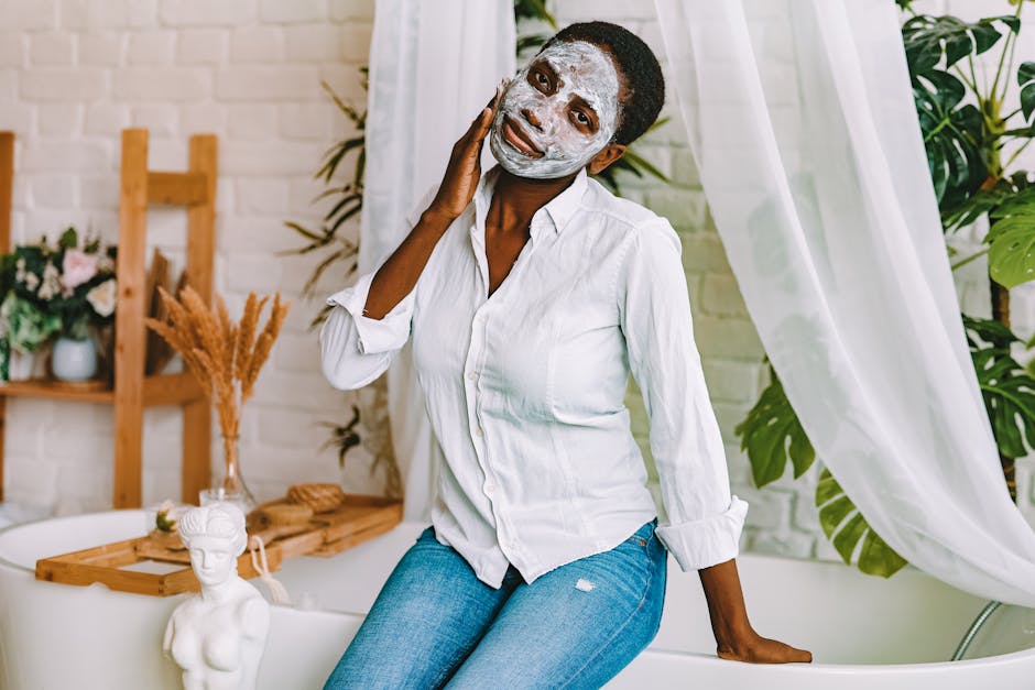 A woman enjoying a skincare routine with a clay face mask, seated indoors with a serene backdrop